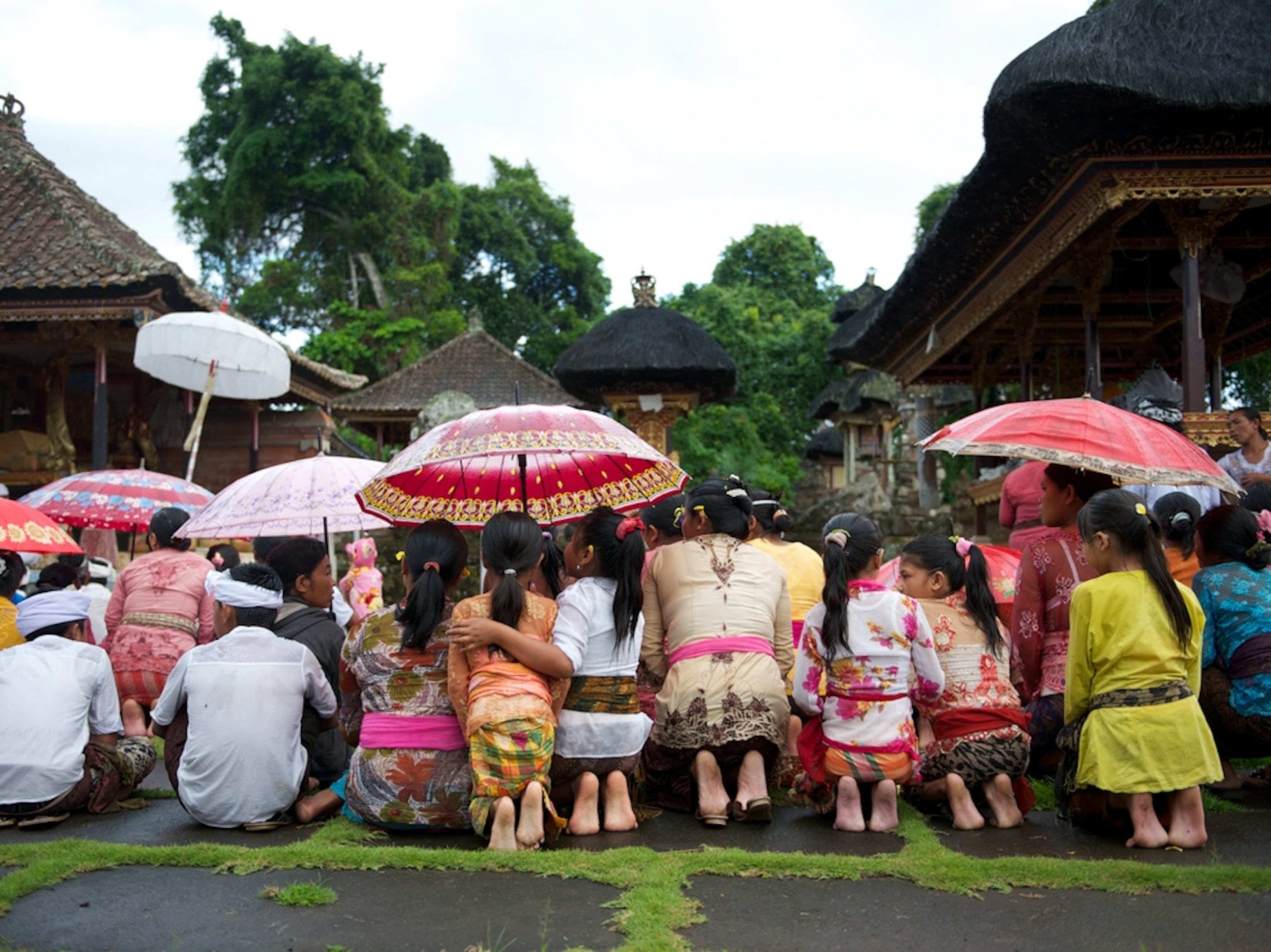 women kneeling in front of a Balinese temple