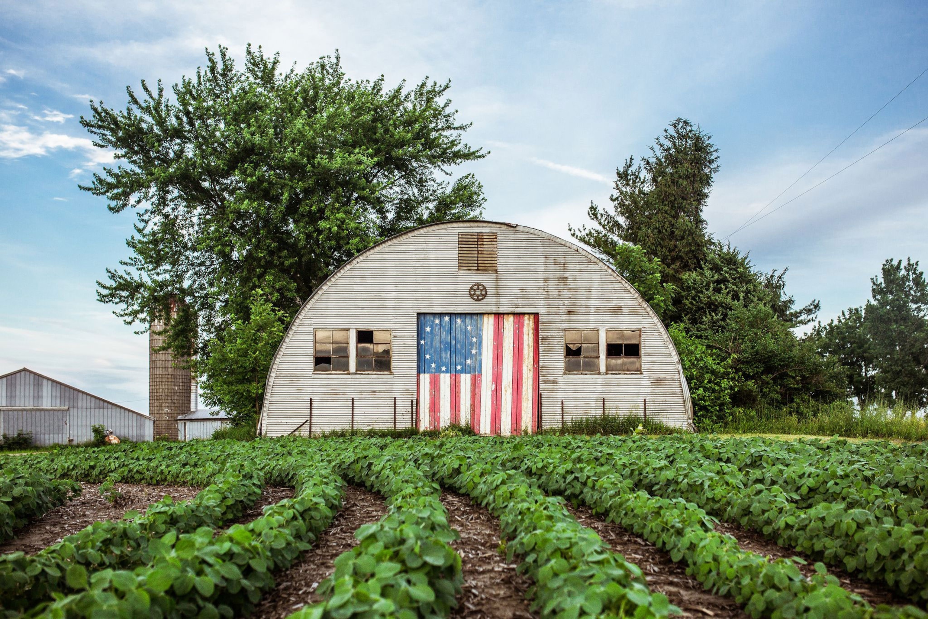 a painted with an American flag, an abandoned warehouse overlooks a spinach field.