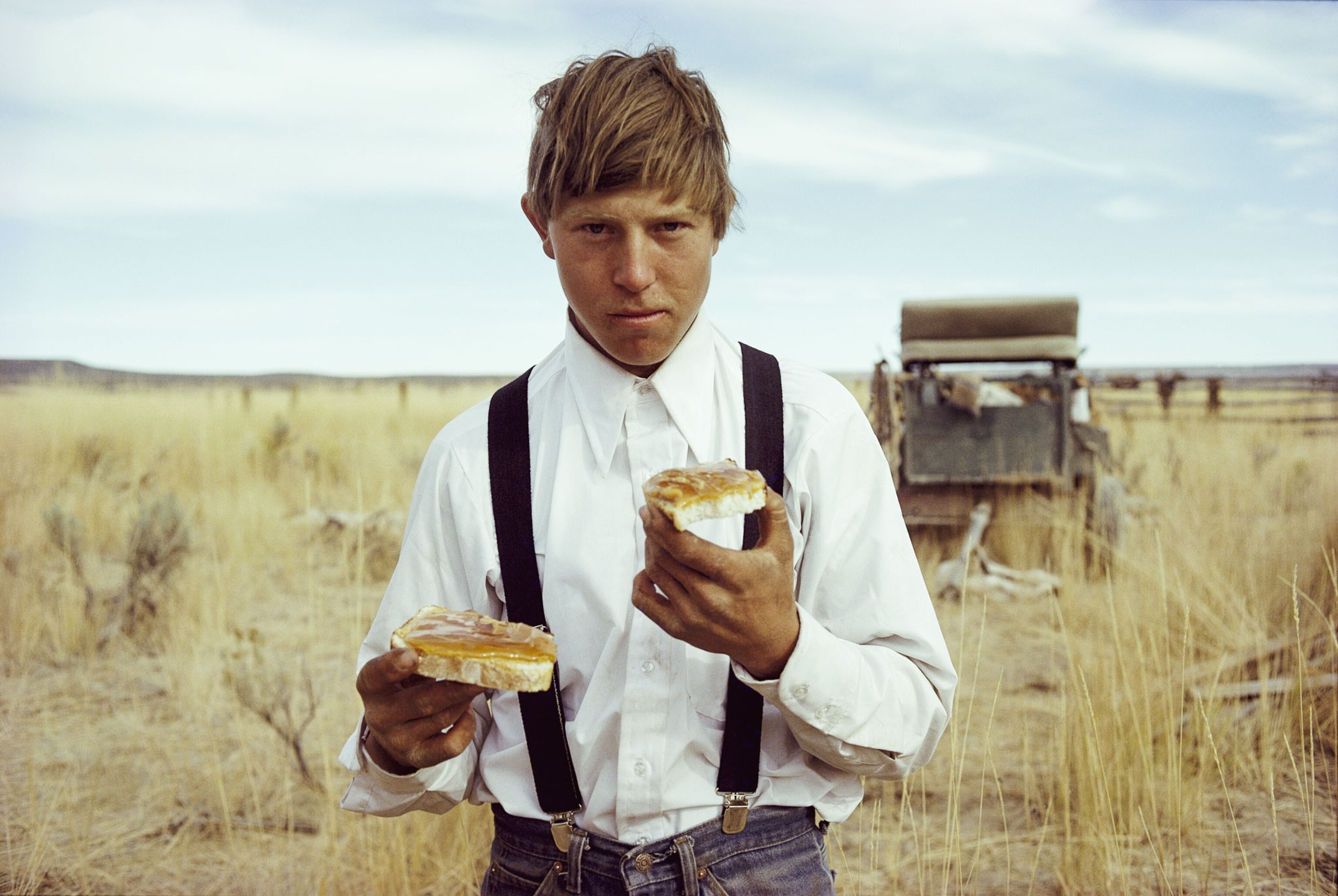 a young cowboy eating a sandwich
