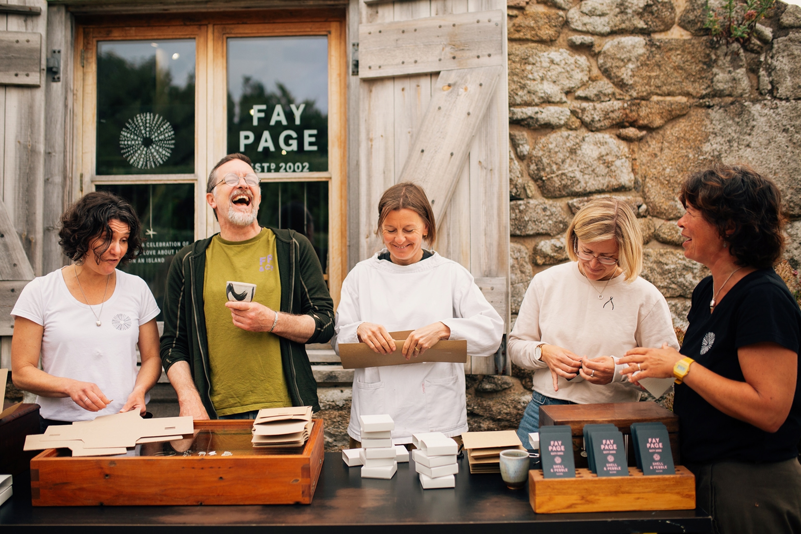 Five people make jewellery outside of a barn workshop.