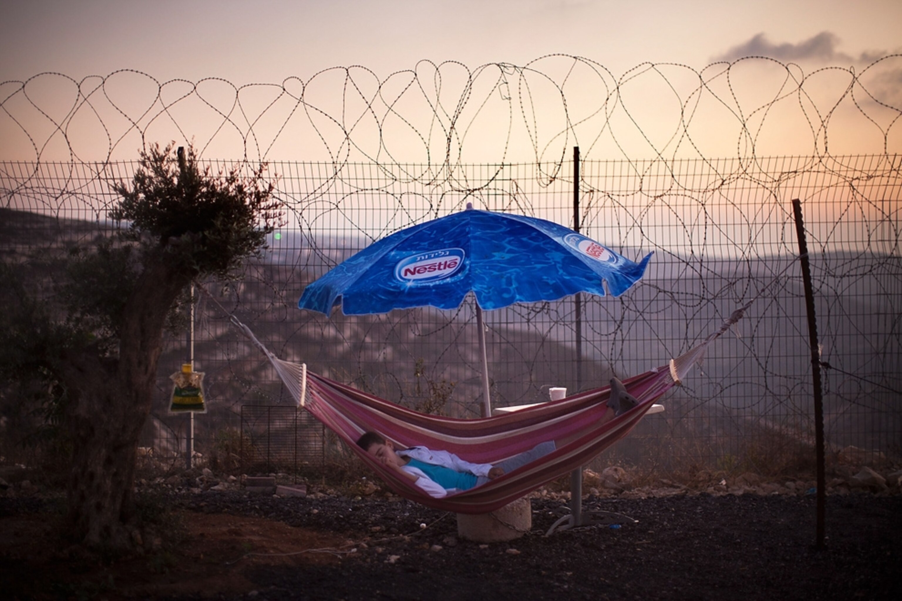 West Bank picture: Israeli boy in a hammock near security fence -- for best pictures of September photo gallery