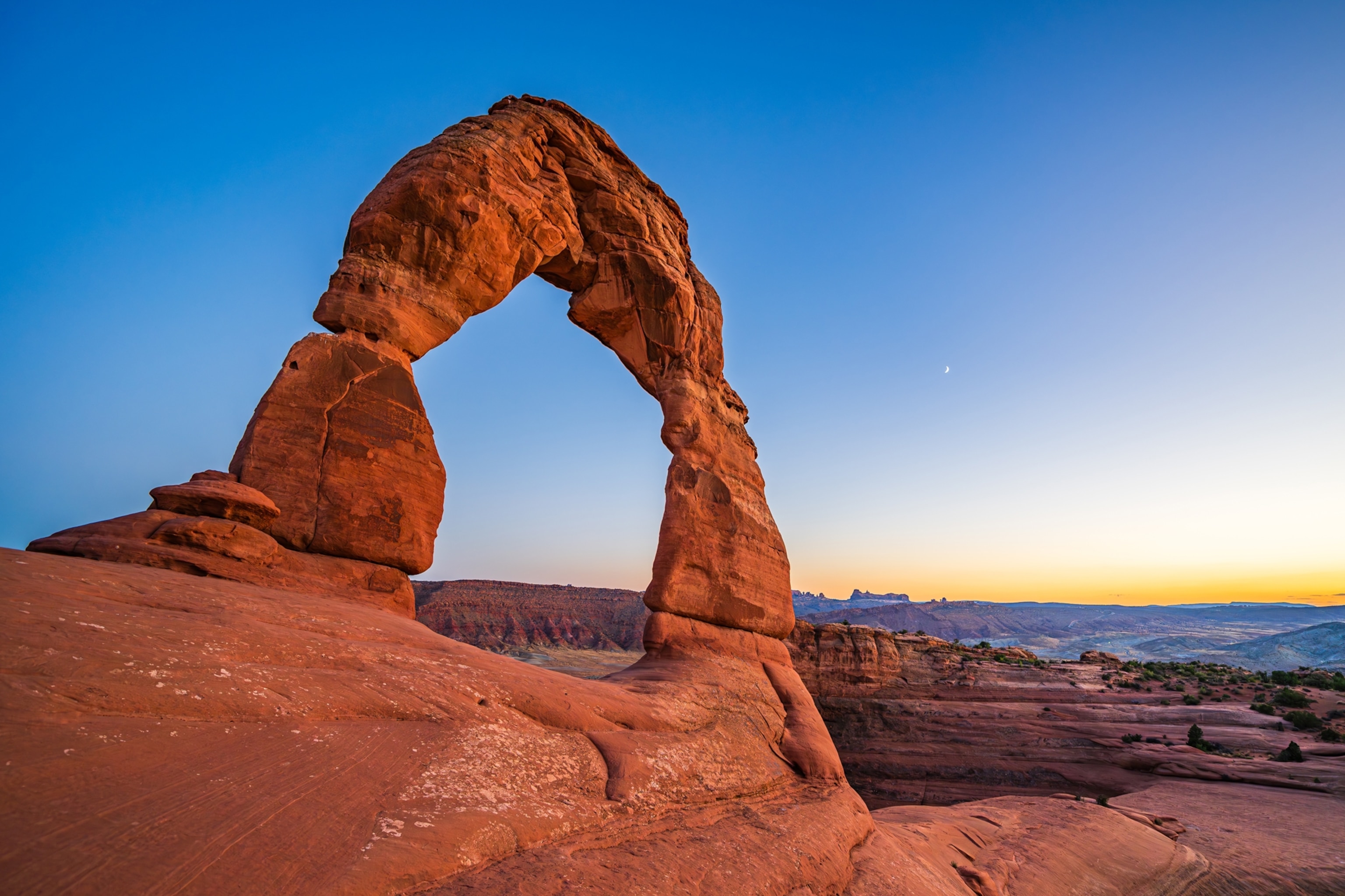 A red rock arch with a blue sky in the background.