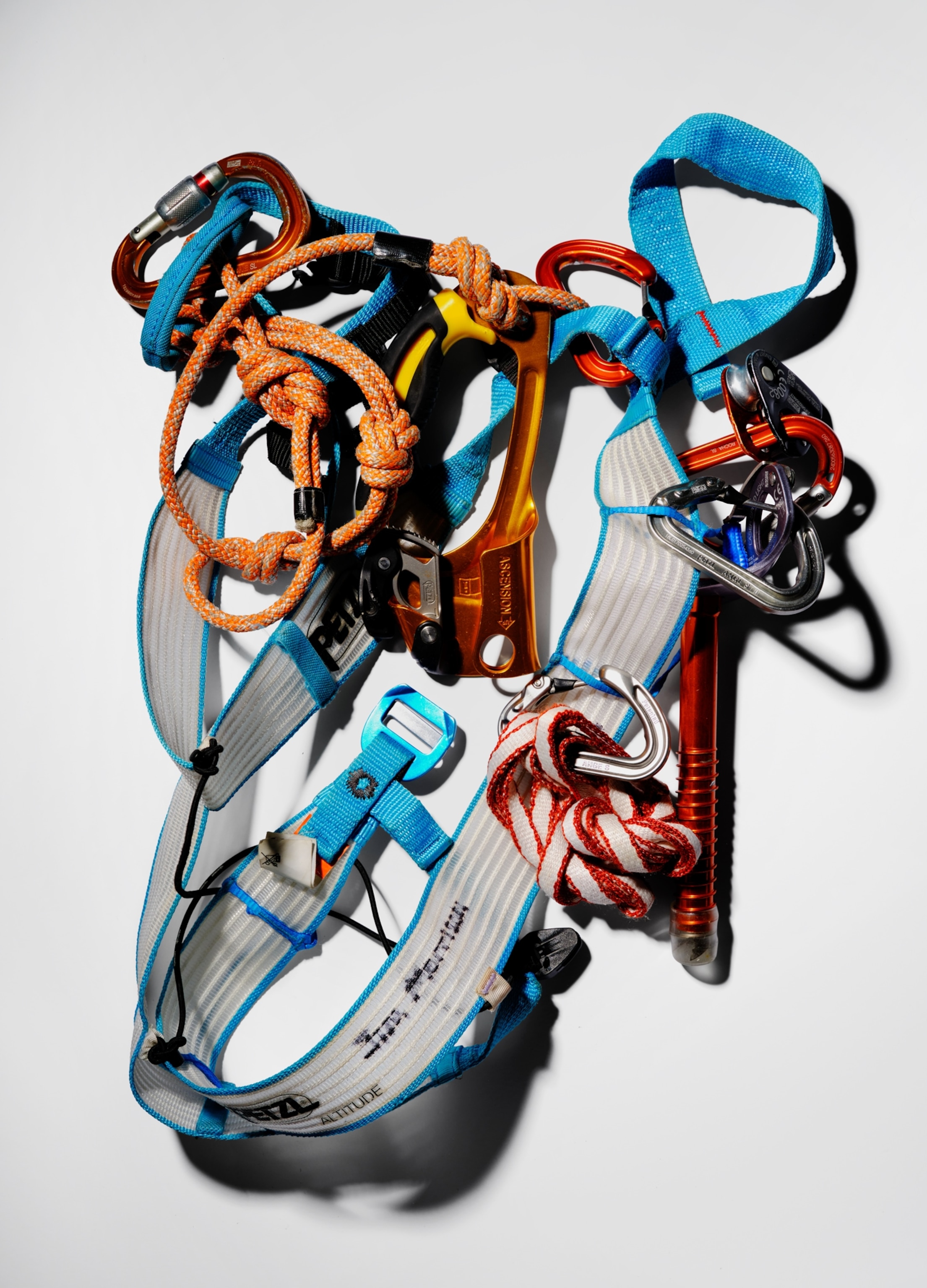 A lightweight mountaineering harness lies on a white background