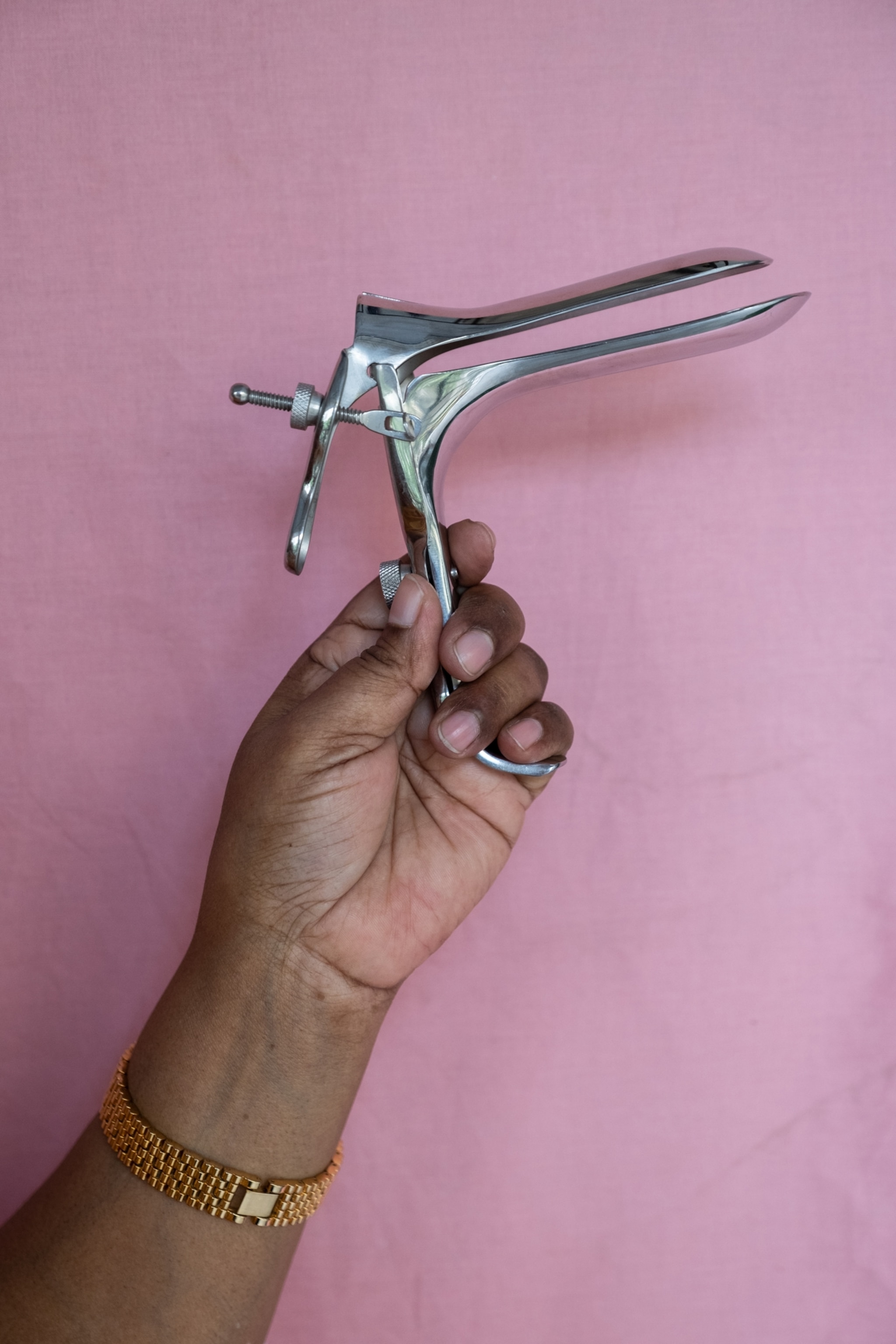A hand holding up a metal speculum.