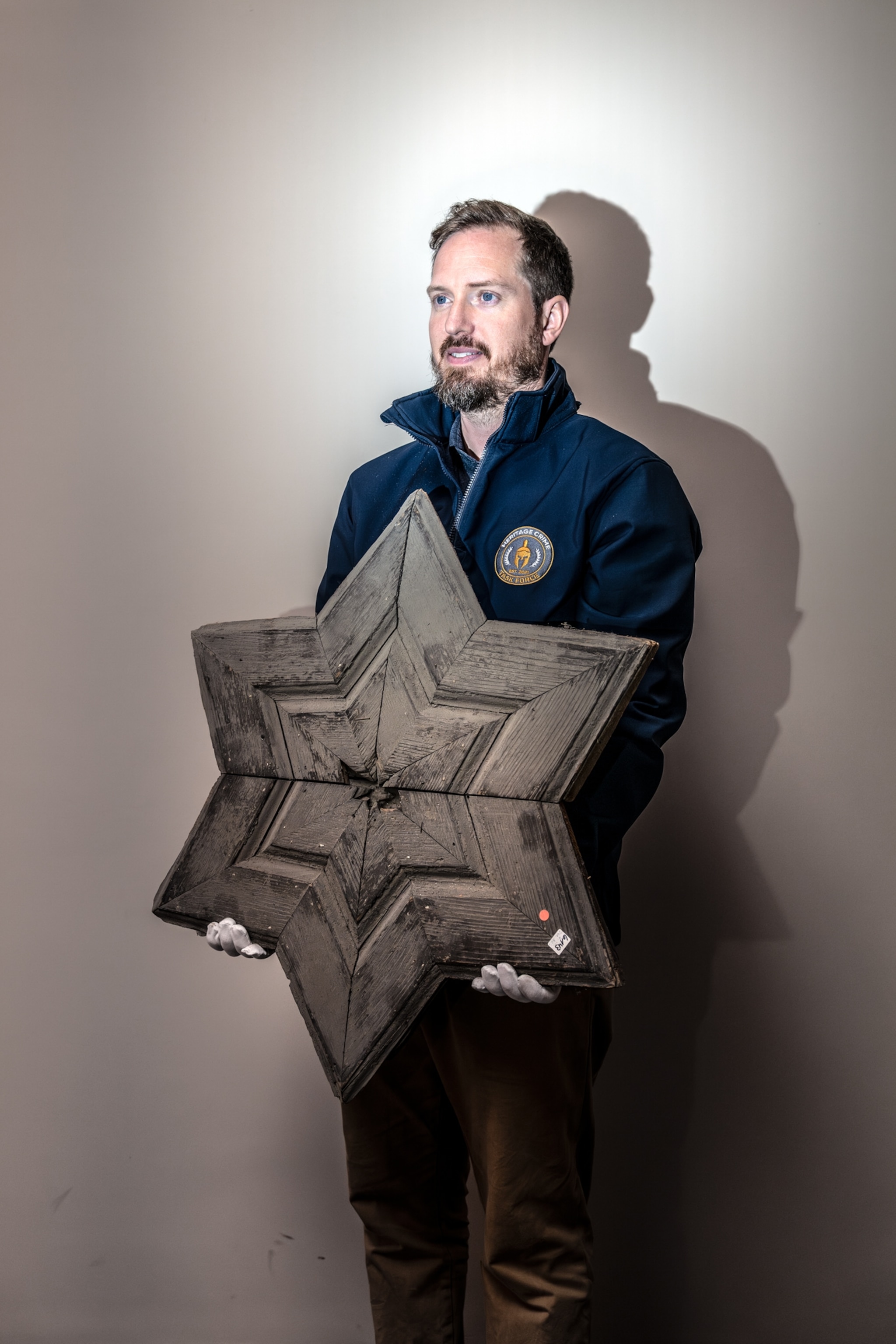 An archeologist holds a wooden panel in a shape of a star