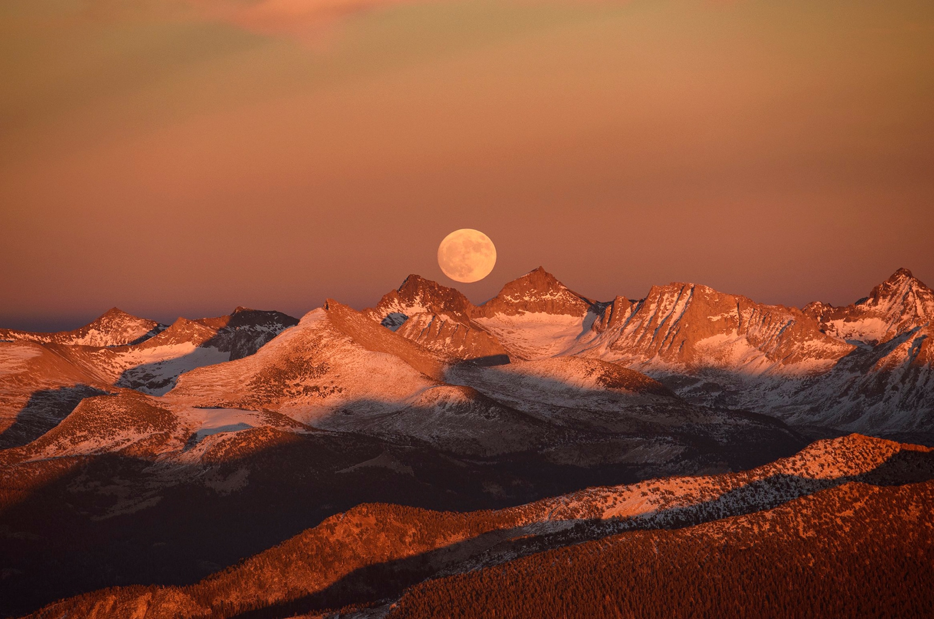 the moon rising over mountains.