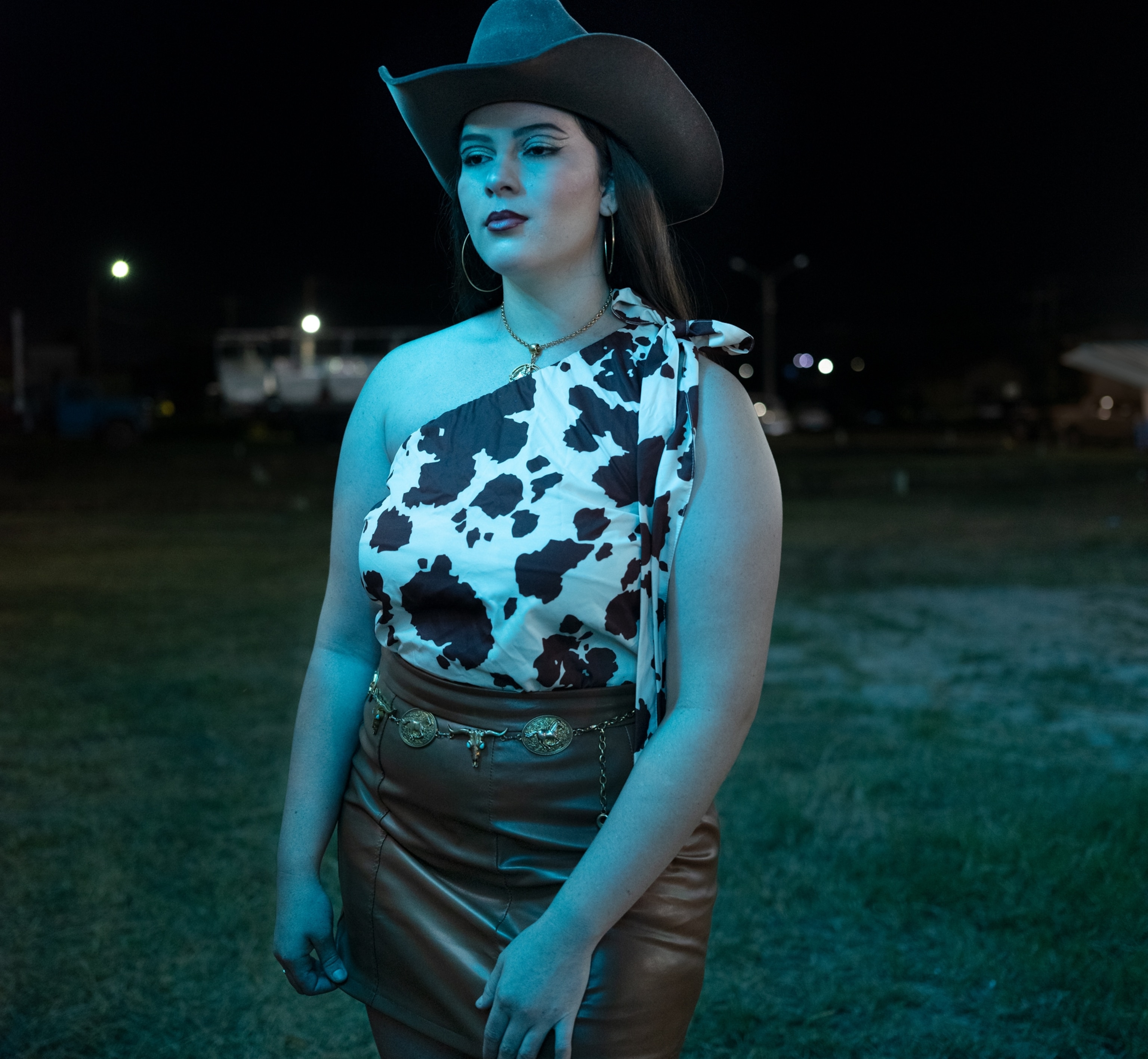 Emilly Narciso Rodrigues pictured wearing a cowboy hat, cowprint shirt, belt, and brownleather skirt