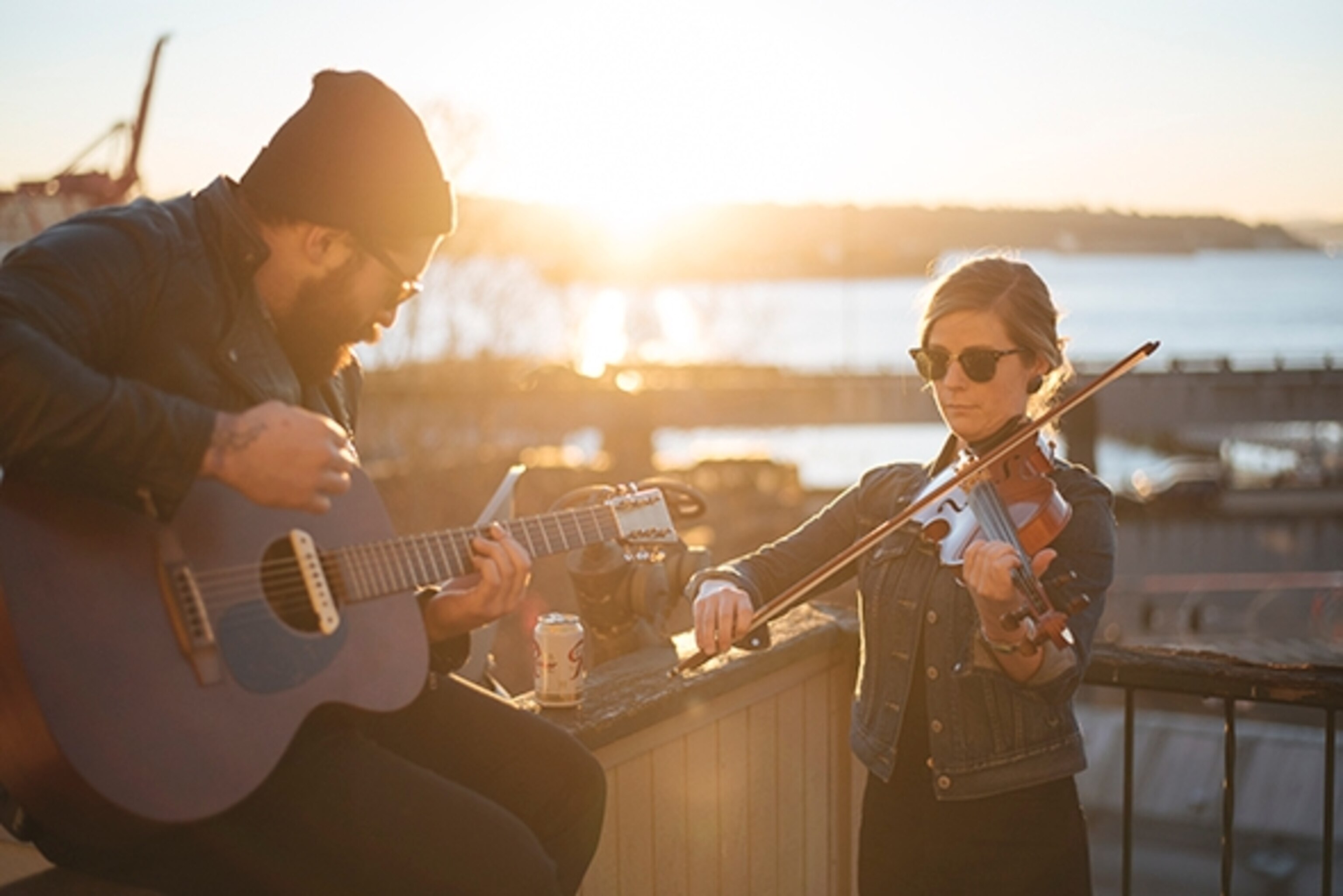 James Anaya, and Maggie Tweedy play music on a rooftop on the waterfront in downtown Seattle, Washington; Photograph by Max Lowe