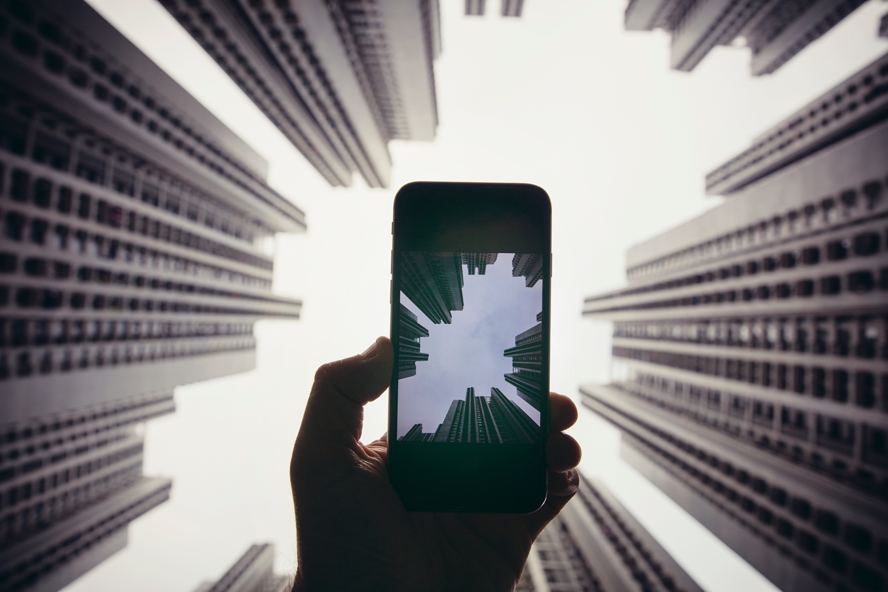 A close-up on a phone taking a picture of skyscraper crowns.