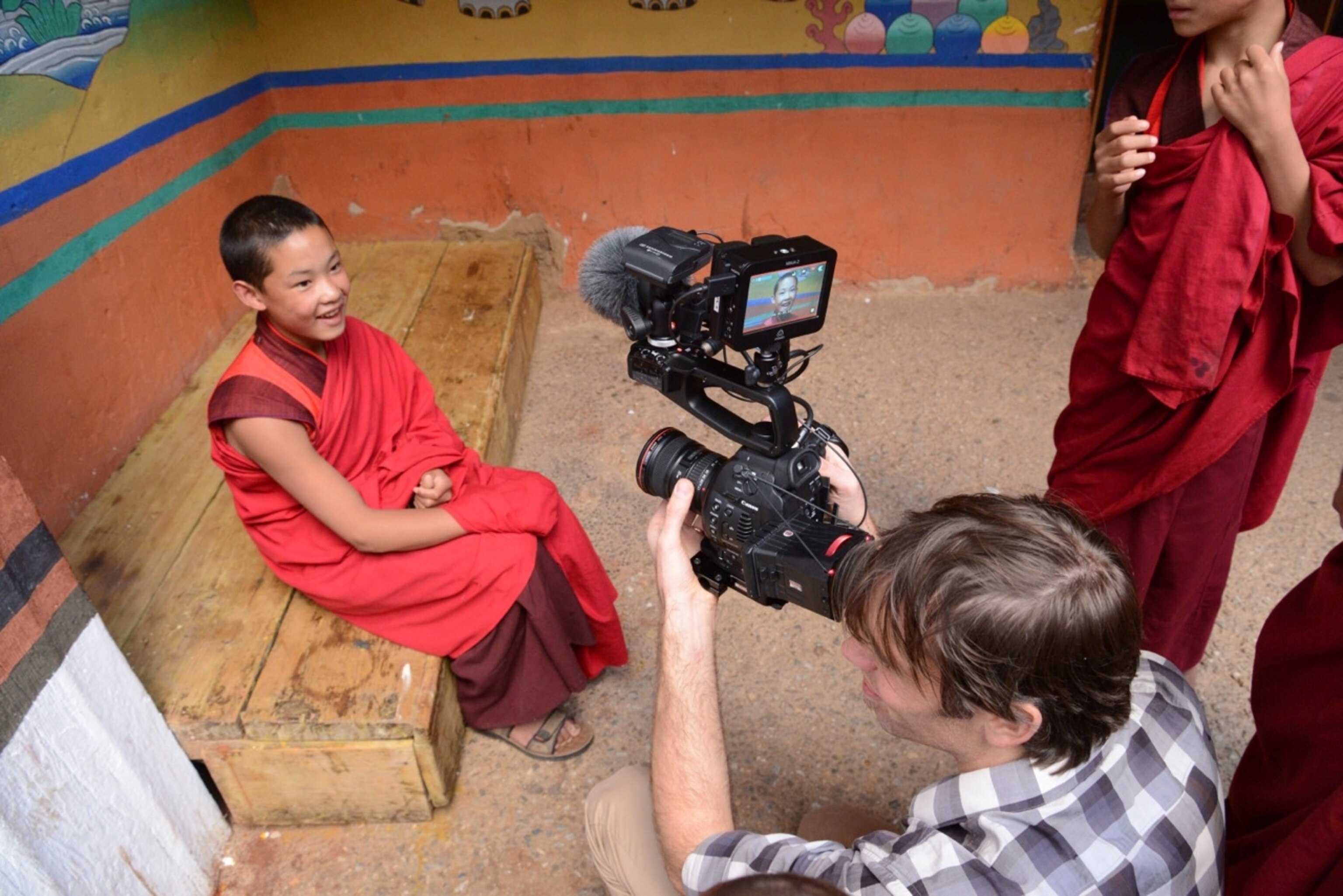 Filmmaker Josh Newman captures a 12-year old monk in Paro, Bhutan during the filming of National Geographic's 125th Anniversary Expedition (Photo by Andrew Evans, National Geographic)