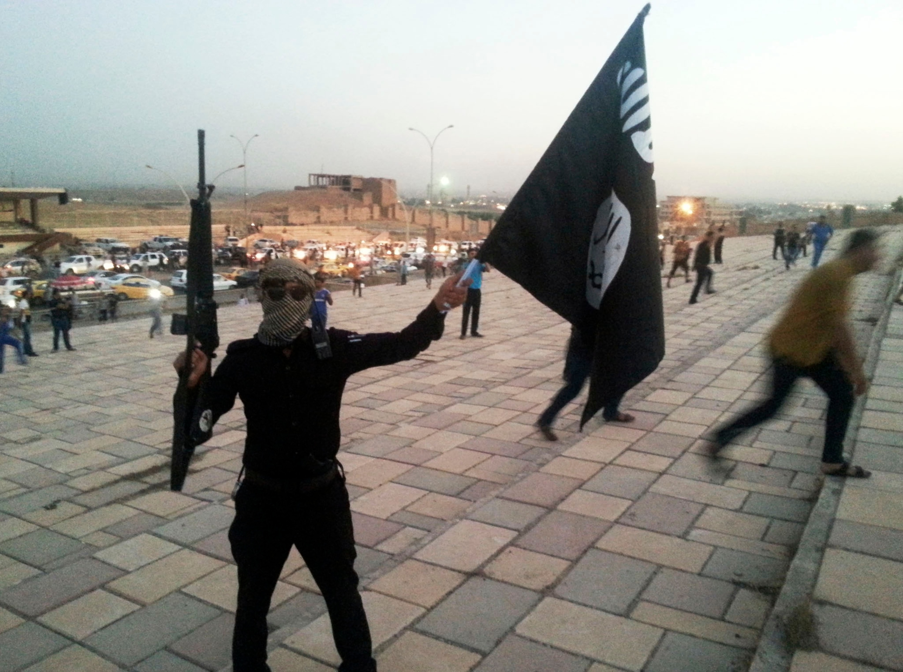 fighter of the Islamic State of Iraq and the Levant (ISIL) holds an ISIL flag