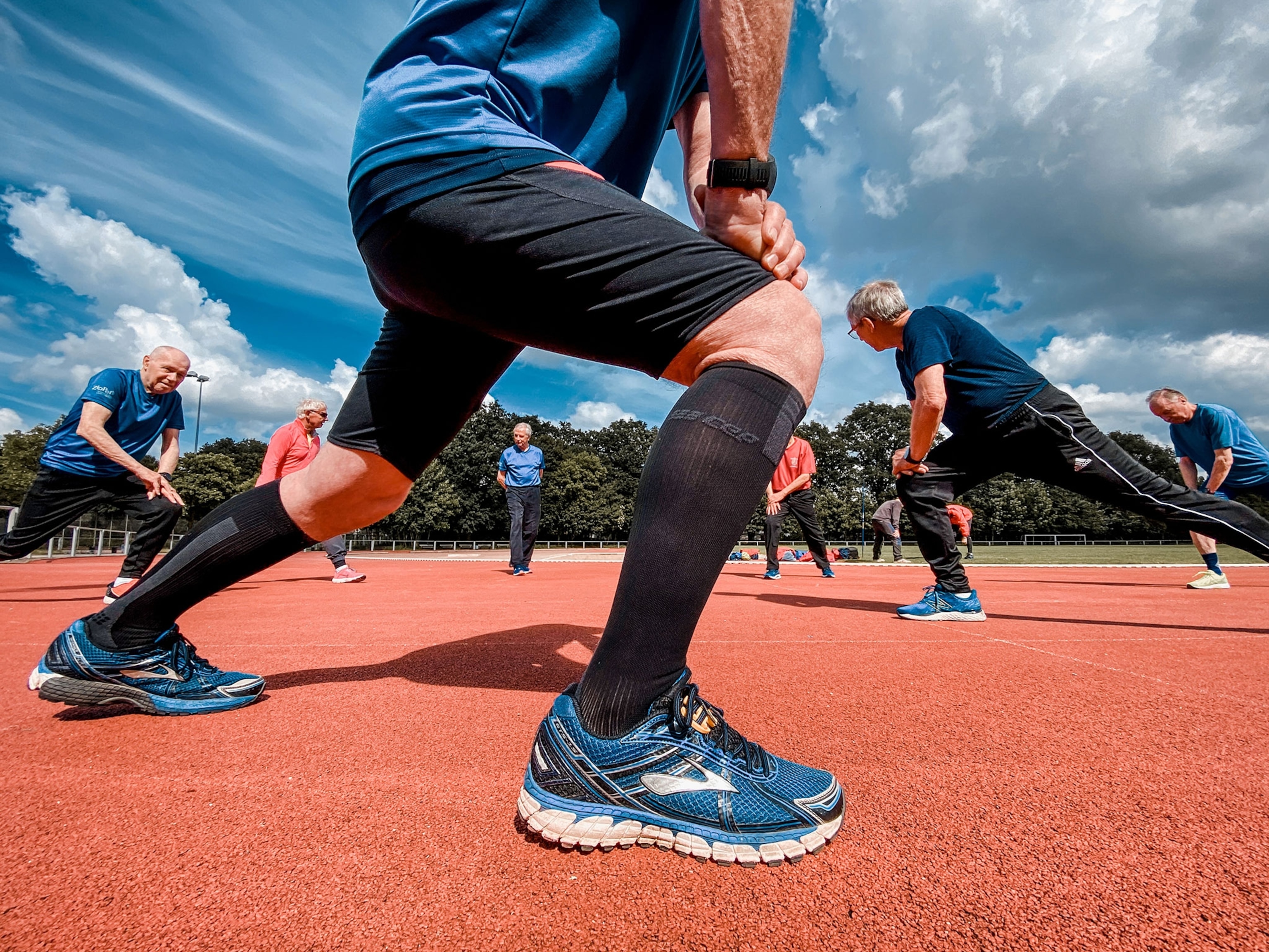 Old men stretching on a field.