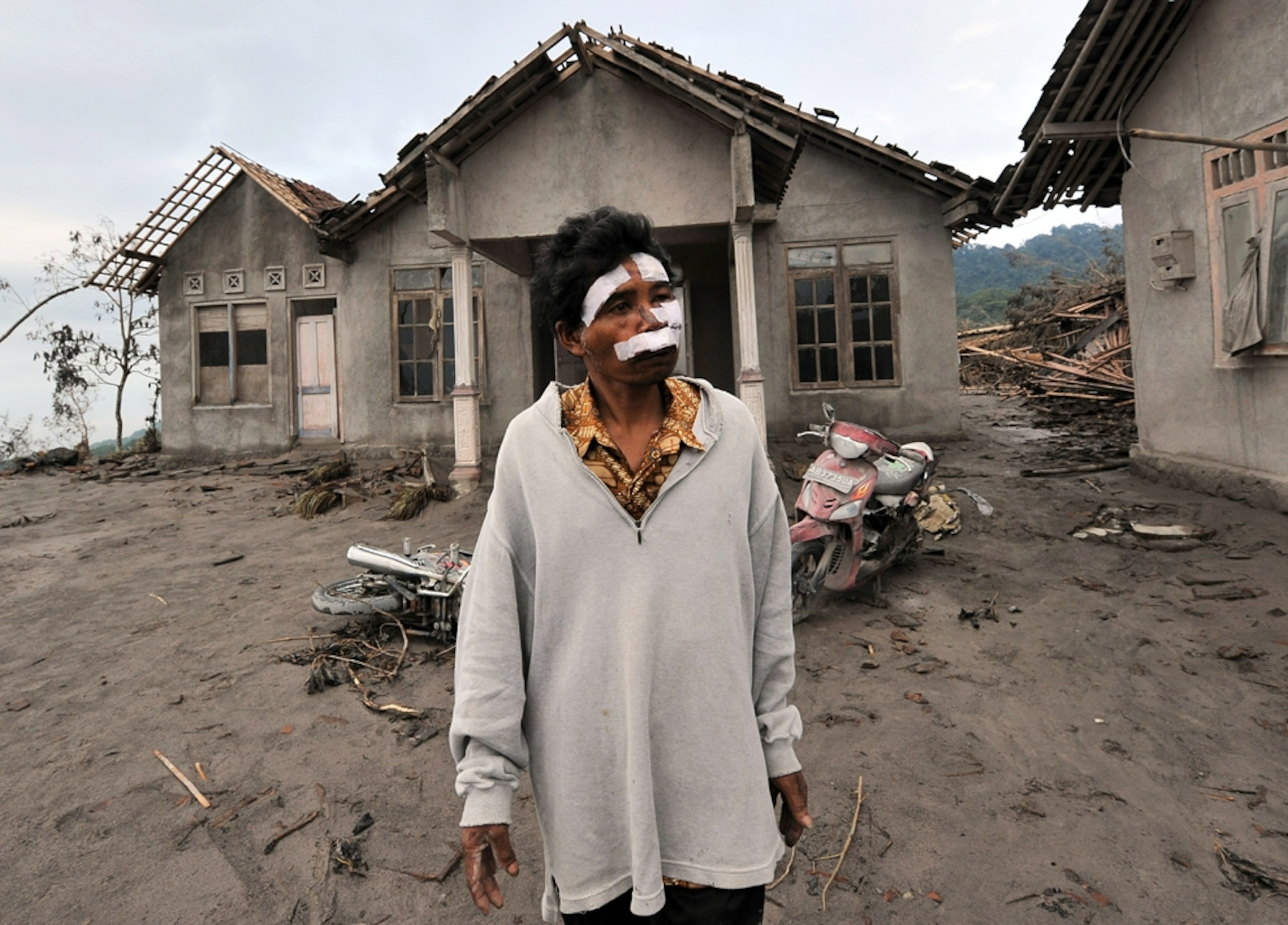 A man whose brother died in the Indonesian Mount Merapi volcano eruption is seen outside a relative's damaged house.
