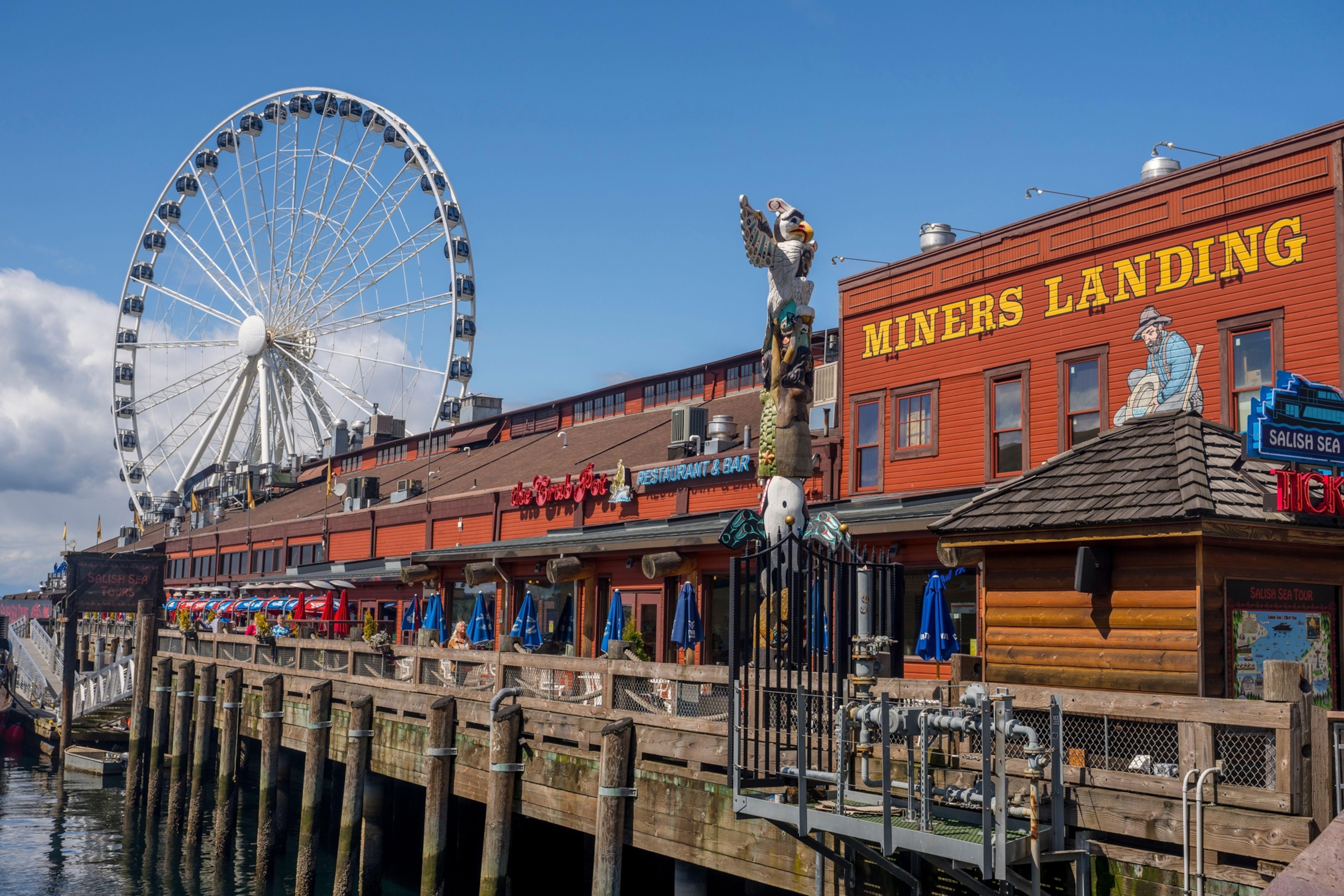 View of the Miners Landing with totem pole and Ferris wheel at the Seattle Waterfront