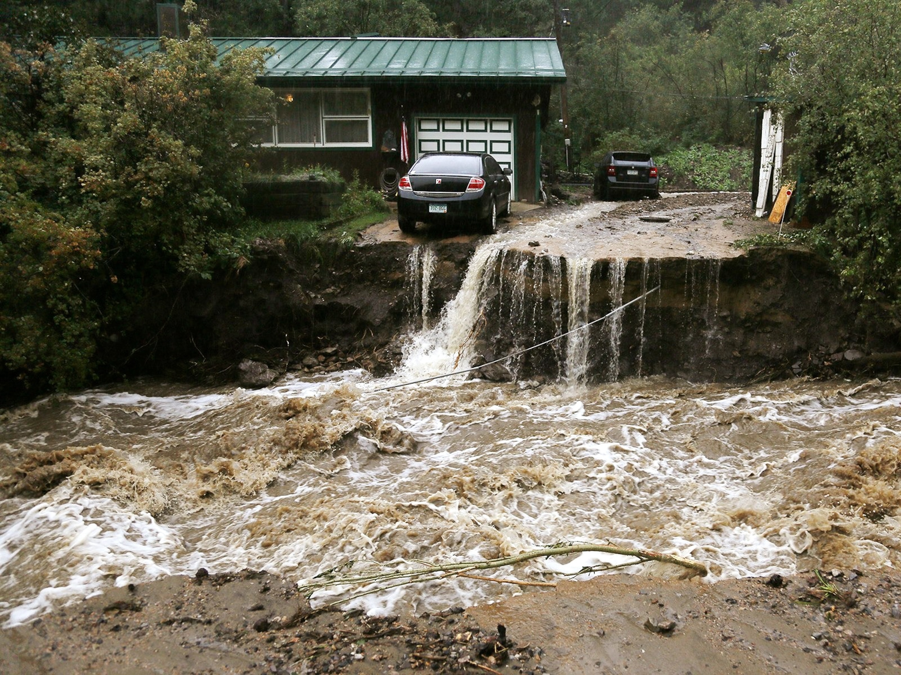 A home and car are stranded after a flash flood in Coal Creek destroyed a bridge near Golden, Colorado.