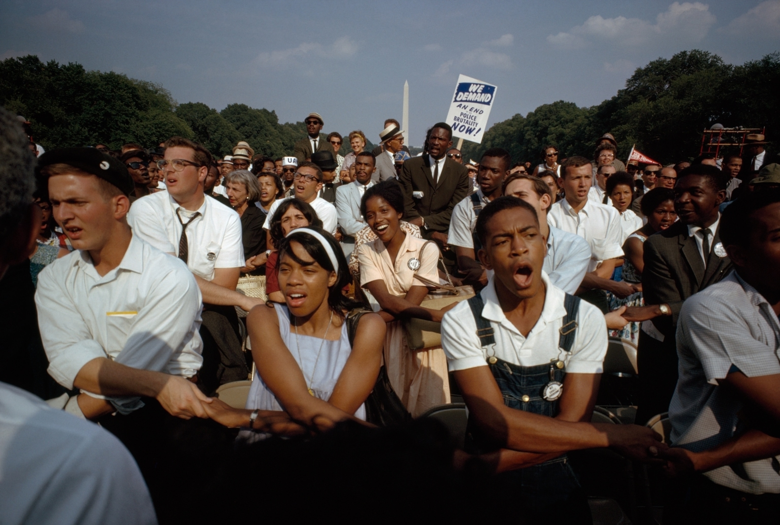 people linking arms in crowd in front of Washington monument