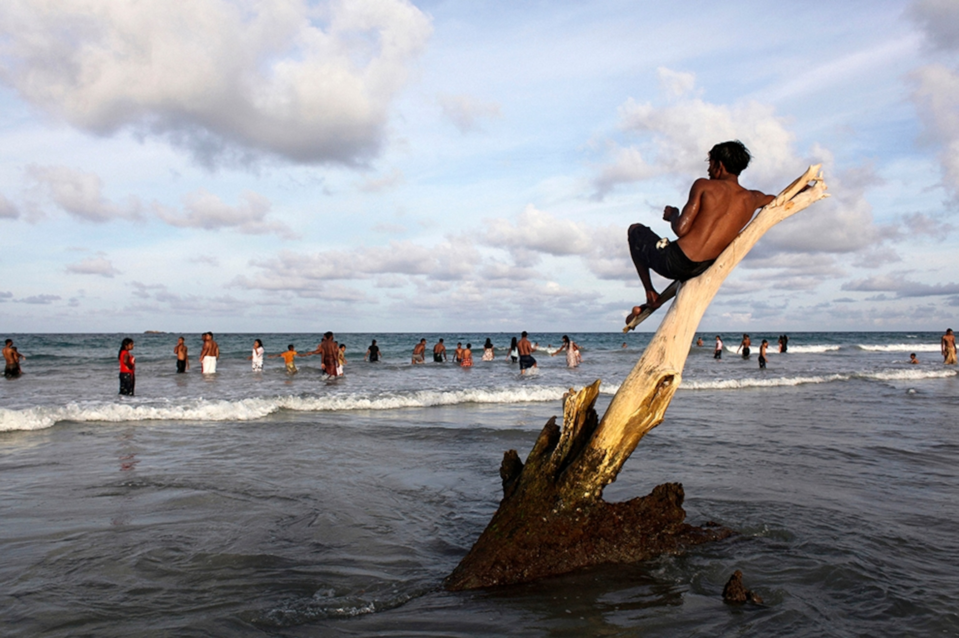 a boy lounging on a tree branch on Nilaveli Beach, East Sri Lanka