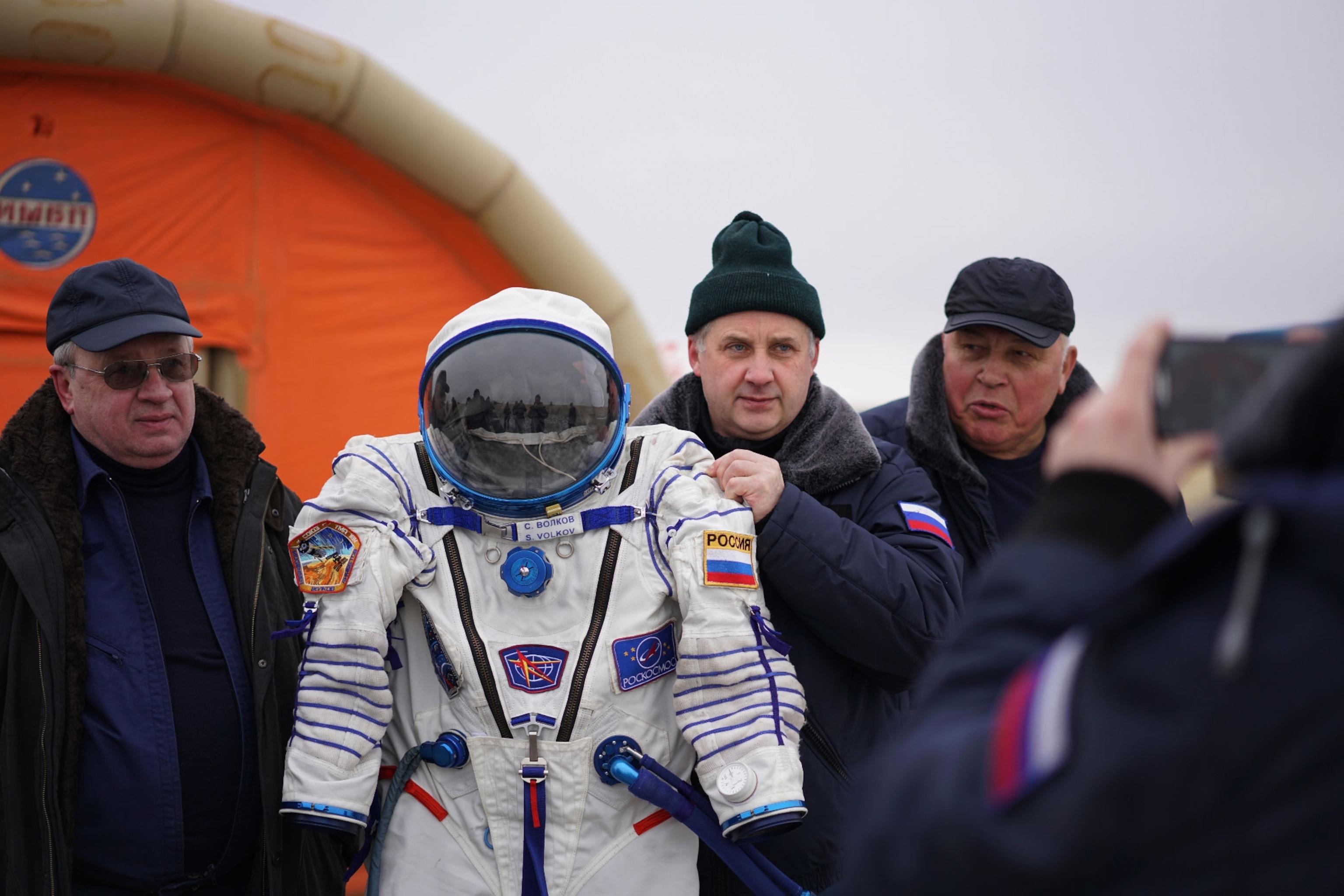 men holding up space suit