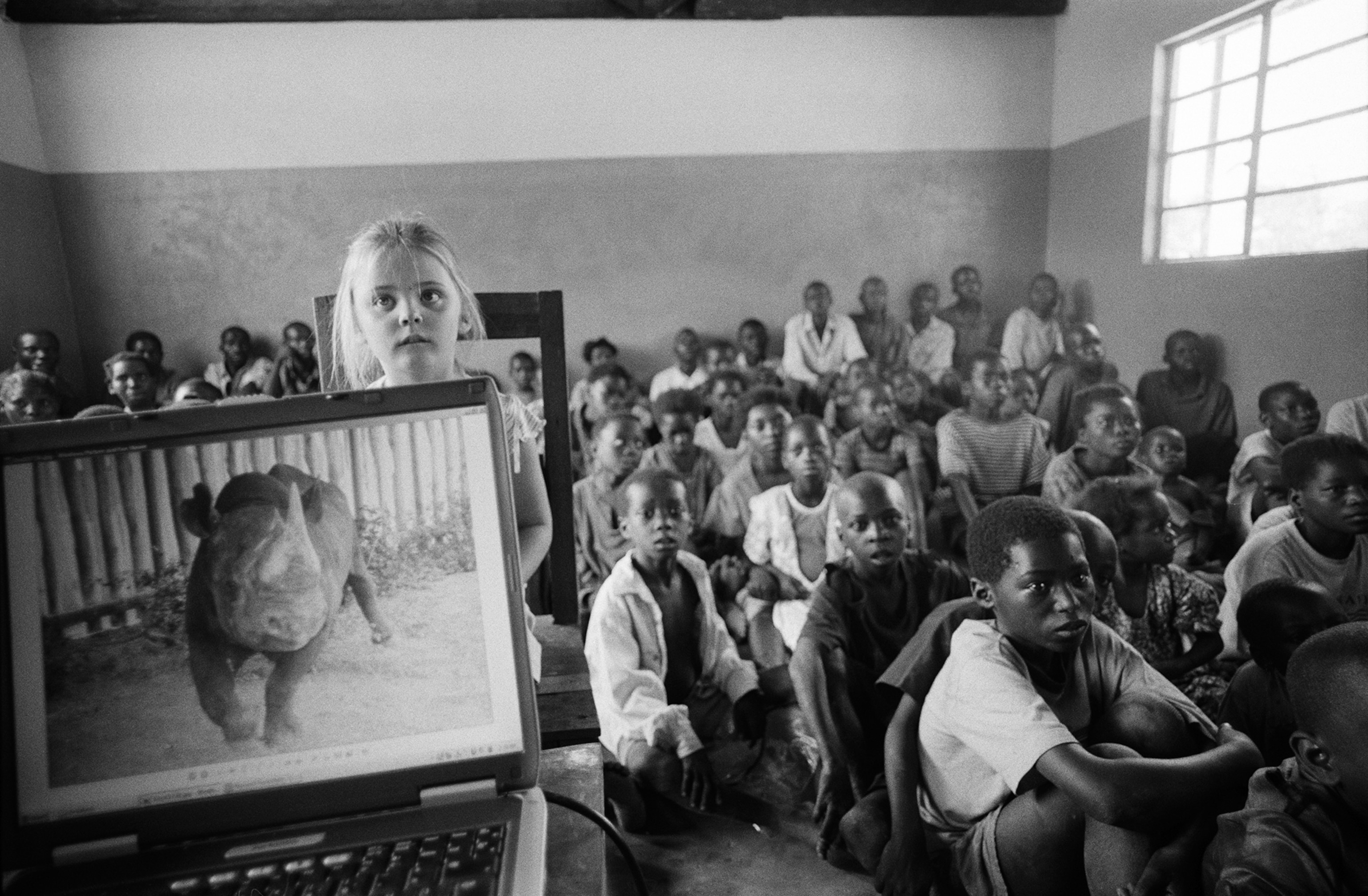 Students in a classroom view photos of reintroduced black rhinos in Chilyaba Community School, Zambia.