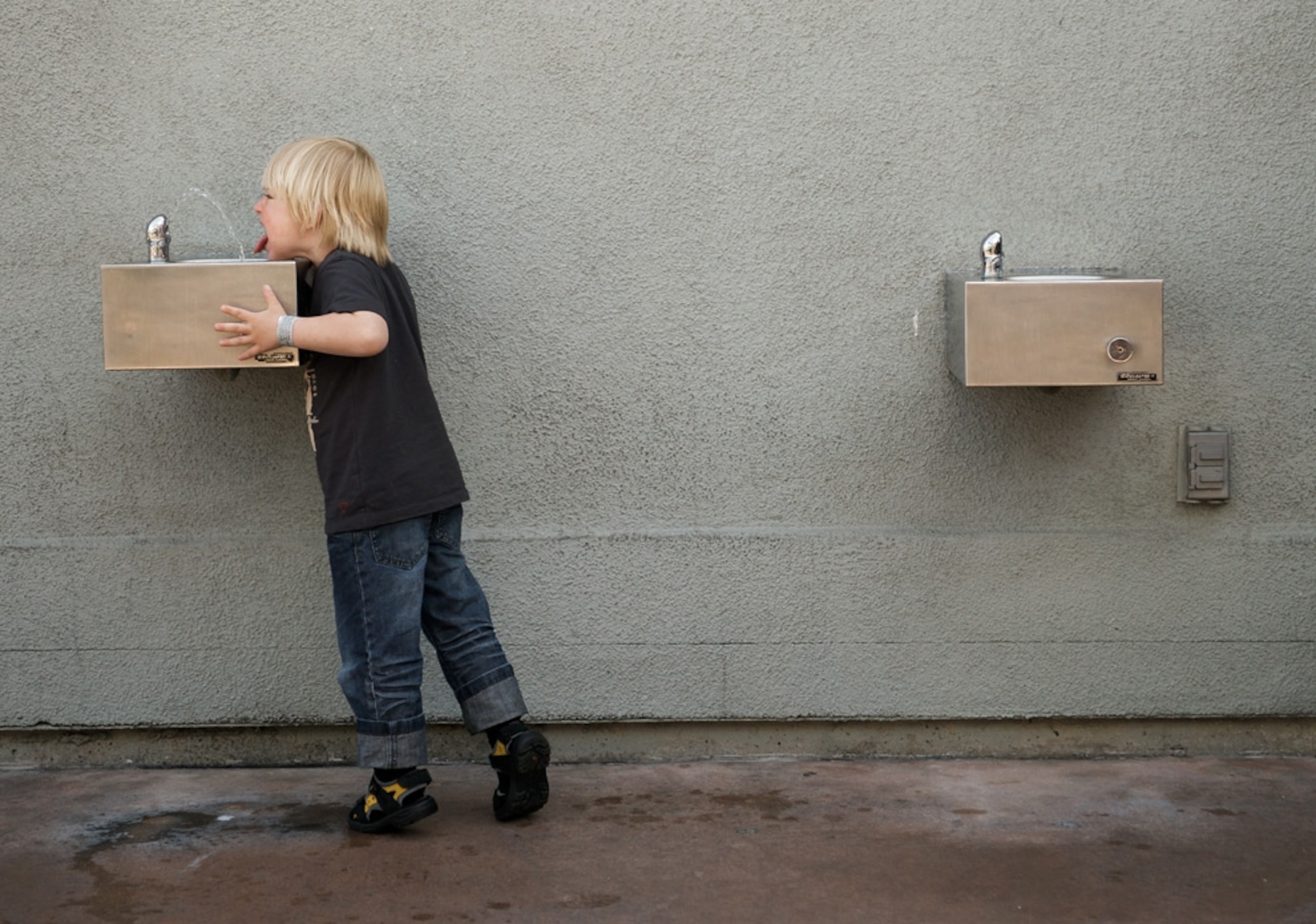 A boy drinking from a water fountain.