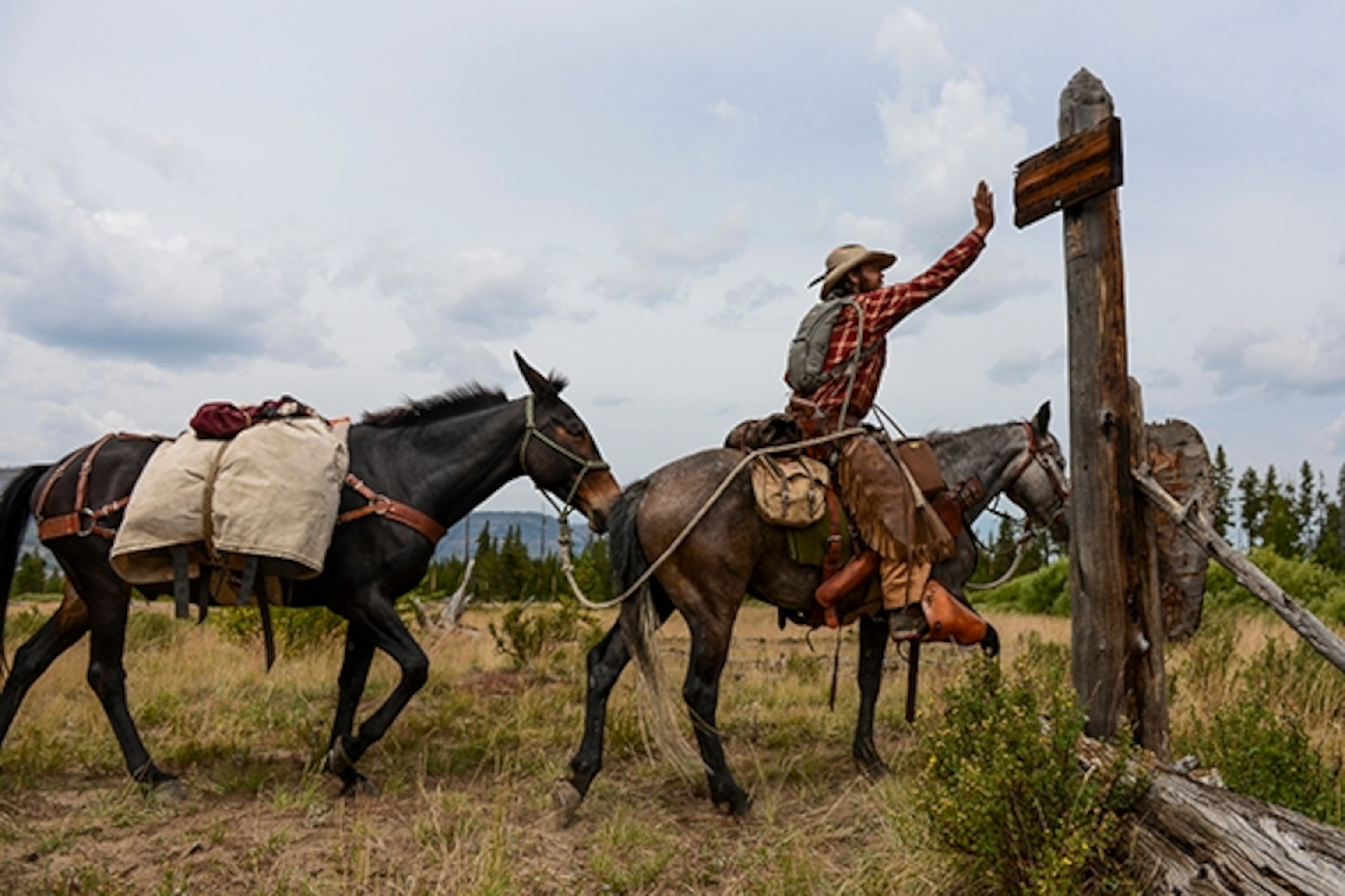 Army Special Forces veteran Ray Knell slaps a sign marking the southern border of Yellowstone National Park as he nears the end of his solo, 1,000-mile ride from Lake George, Colorado, to Manhattan, Montana; Photograph by Michael Ciaglo