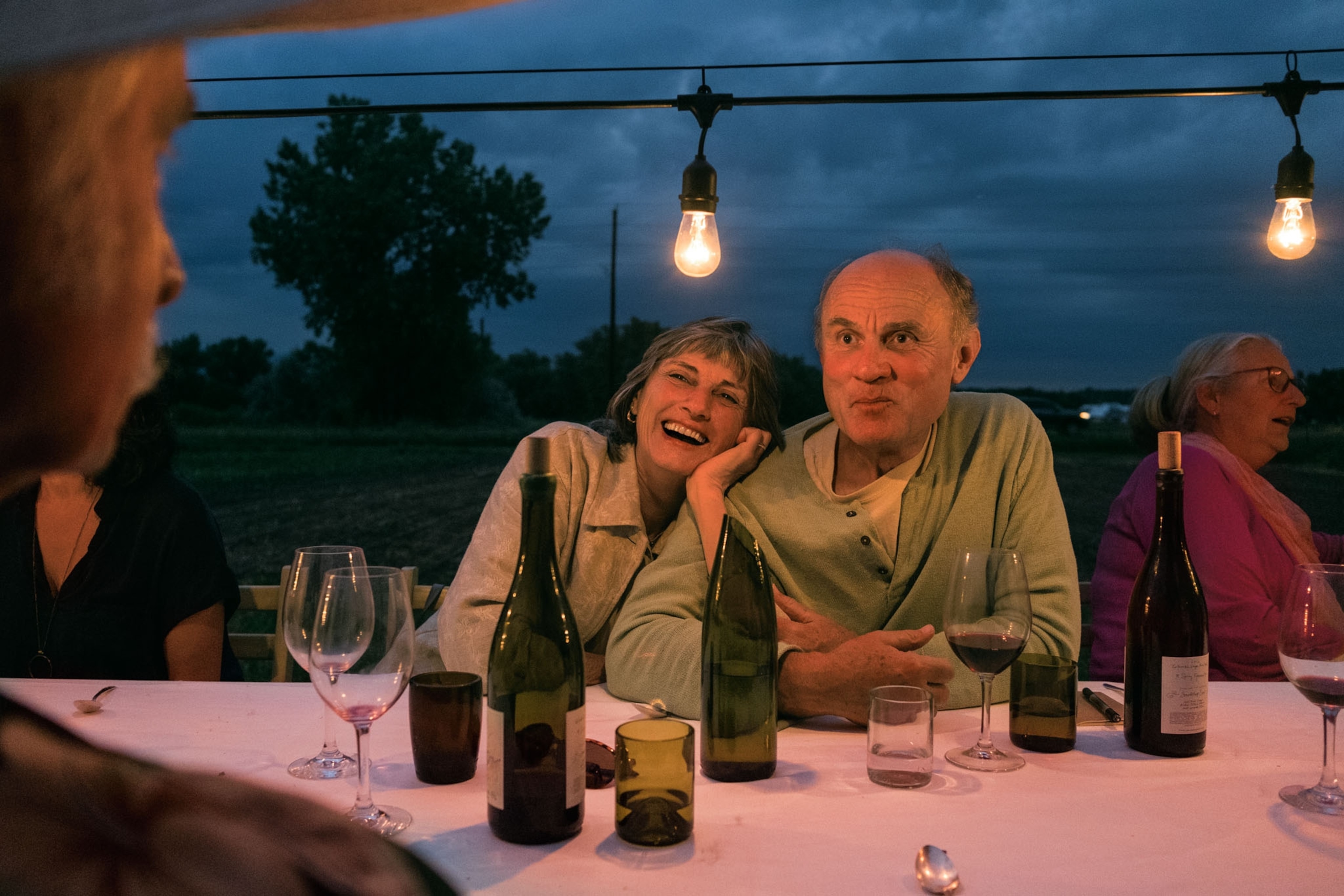 smiling couple having drink with friends in evening on an organic farm outside Boulder.
