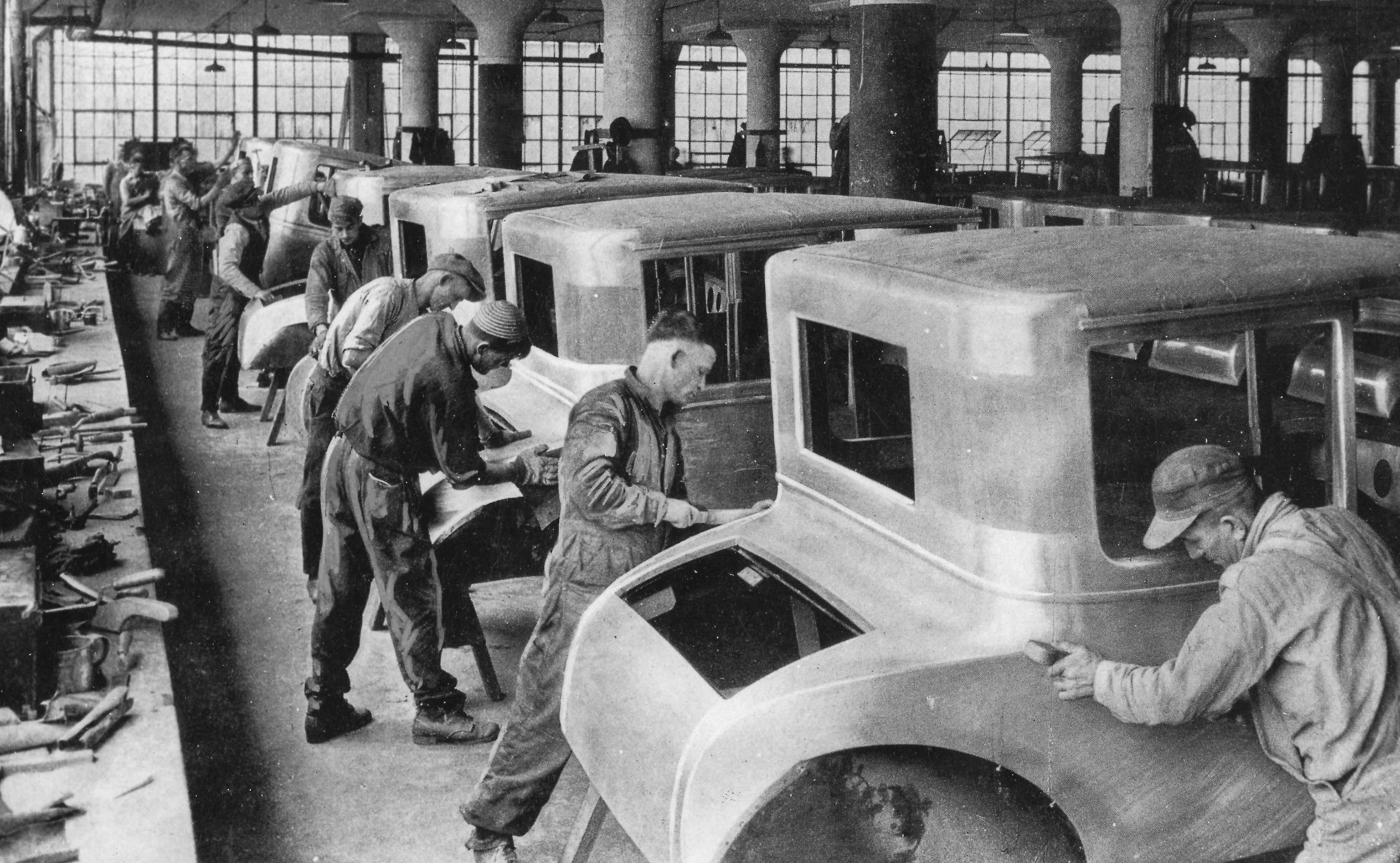 A group of men working on an assembly line of car bodies at the Ford motor plant in Detroit