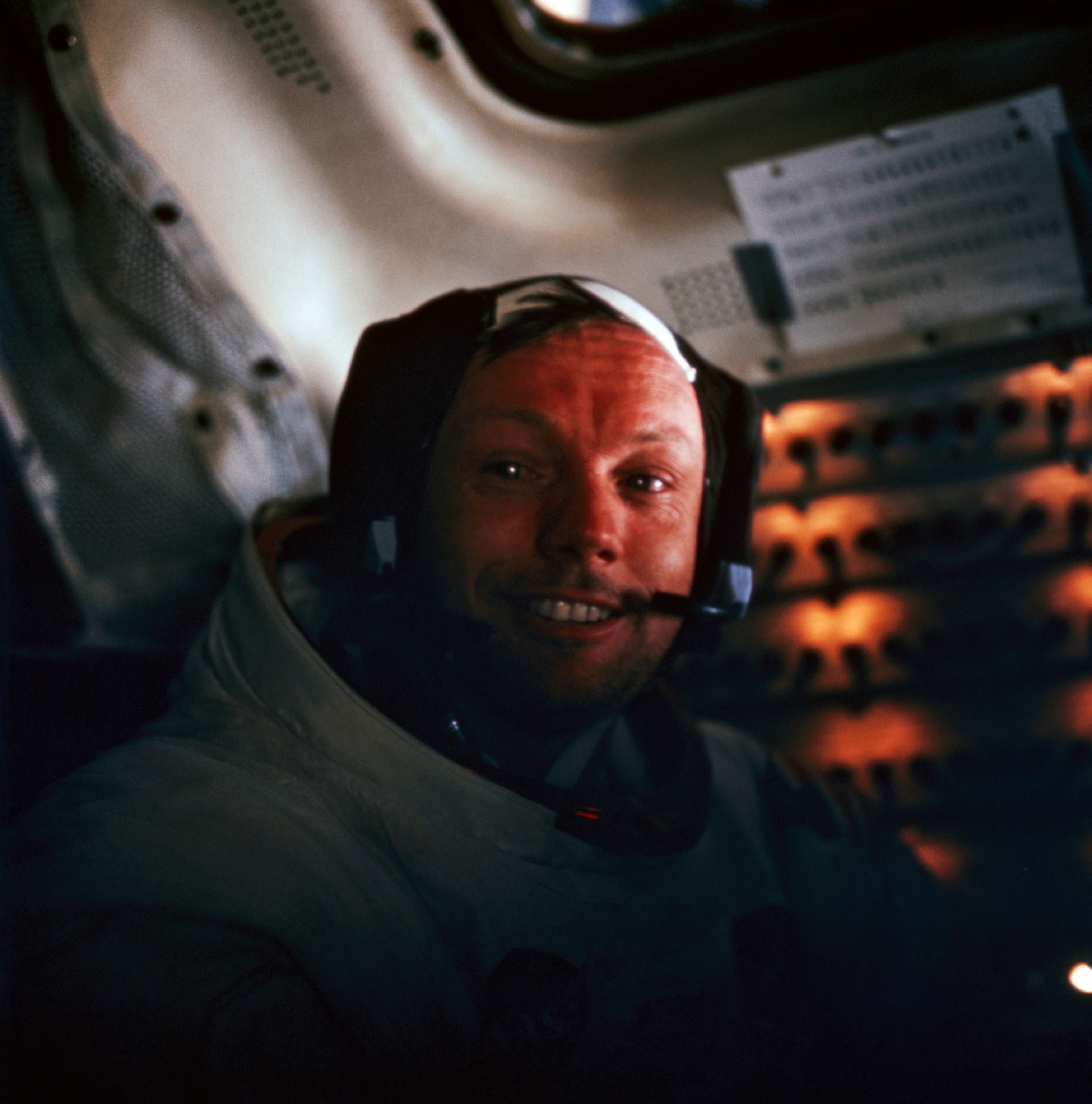 Back inside Eagle after his two hours and twenty minutes outside the spacecraft, moon explorer Armstrong wears a grin as he talks into a microphone to Houston. Safely aboard are the prized samples of soil and rock.