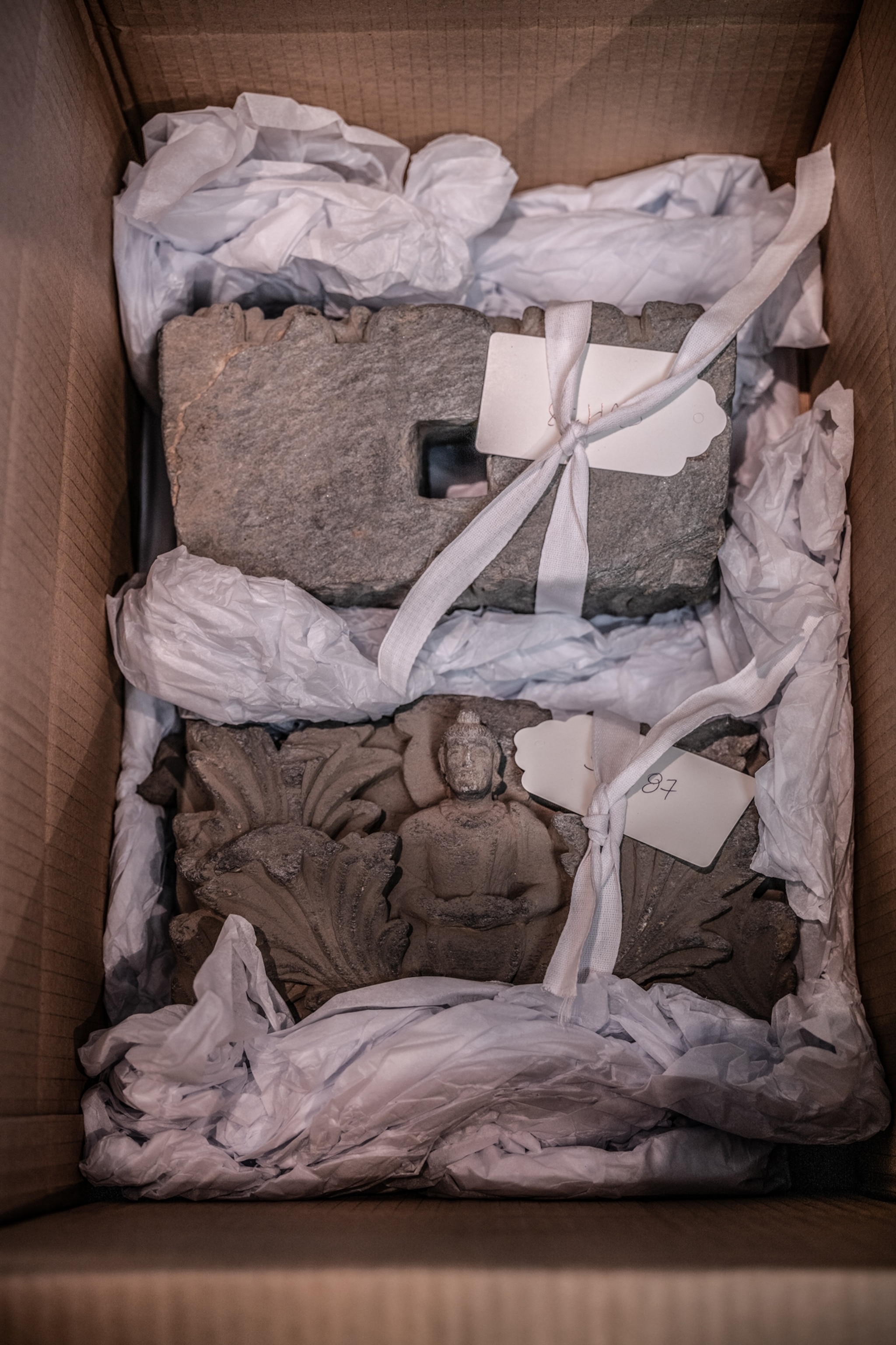 Artifacts surrounded by white packing materials in a cardboard box