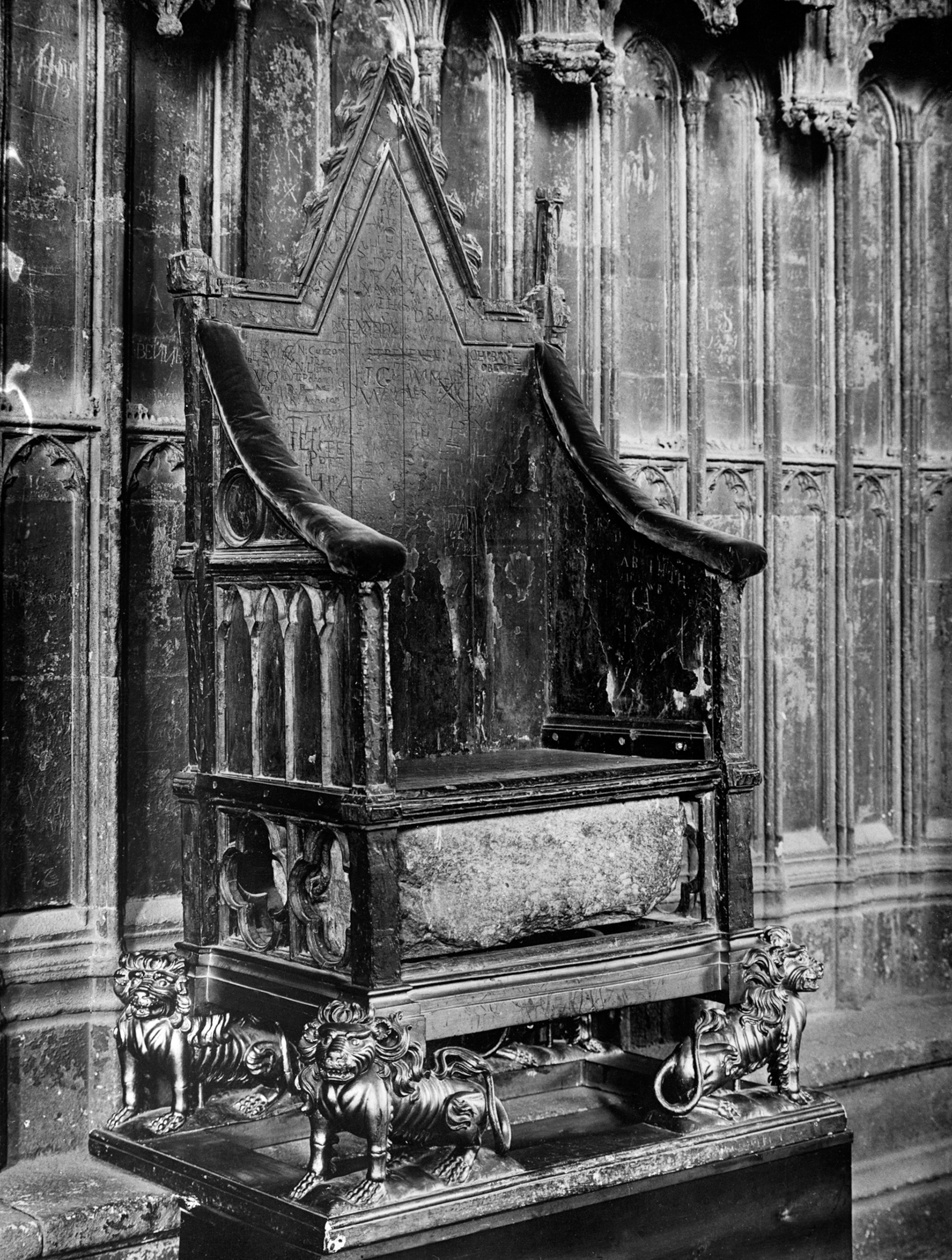 A black and white photo of a throne and a stone sits underneath.
