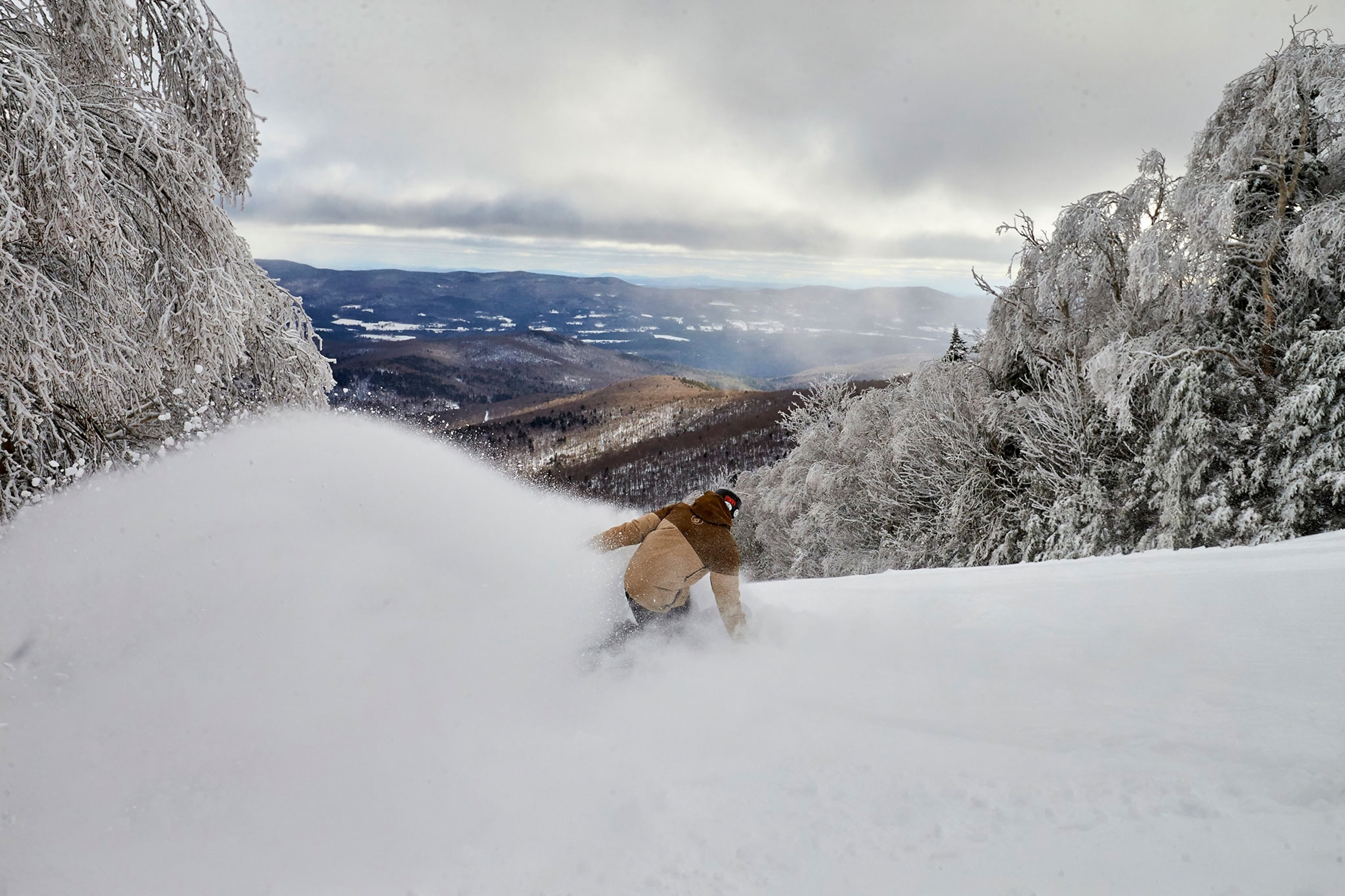 a snowboarder slashing powder inbounds at Sugarbush, Vermont