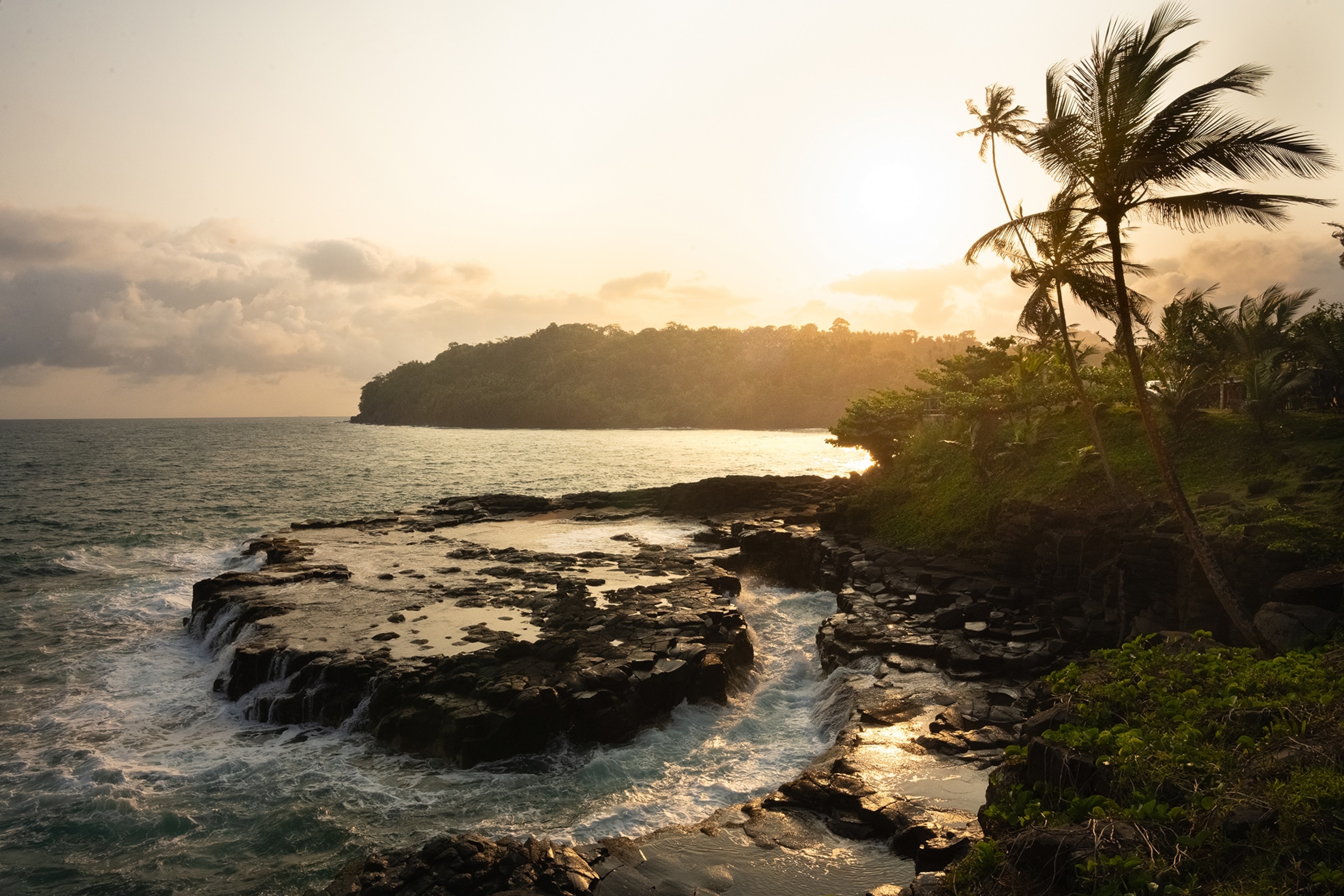 A rugged coast with river enclaves as the water washes up on the rocks at sunset.