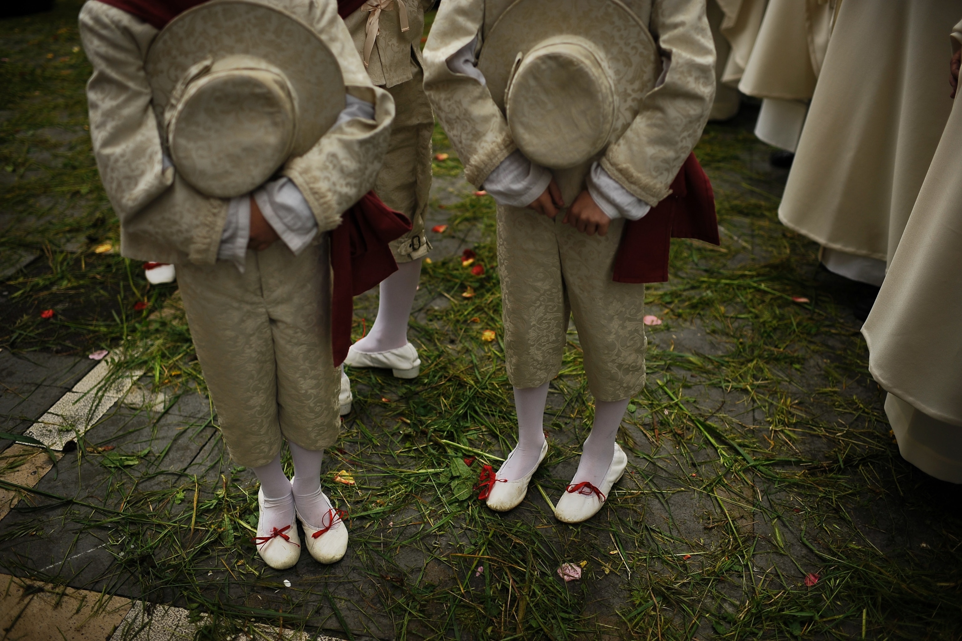 two people standing on a grass-covered street during procession of Corpus Christi in Spain