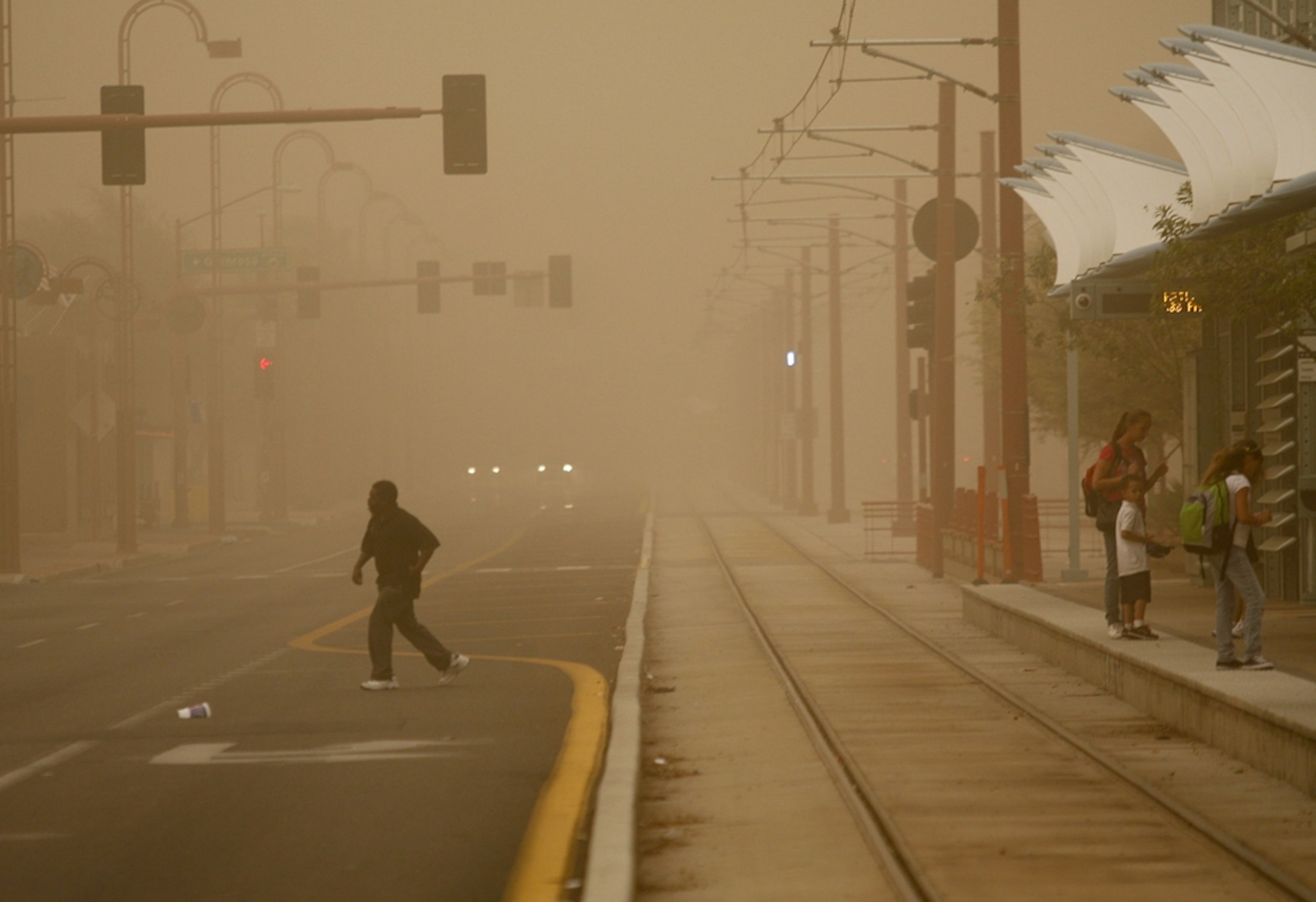 a person crossing a road obscured by a dust storm